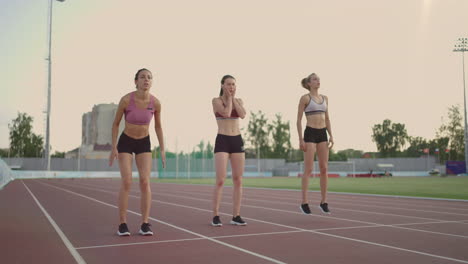 3-women-runners-prepare-for-the-long-distance-race-at-the-stadium-at-sunset-in-slow-motion